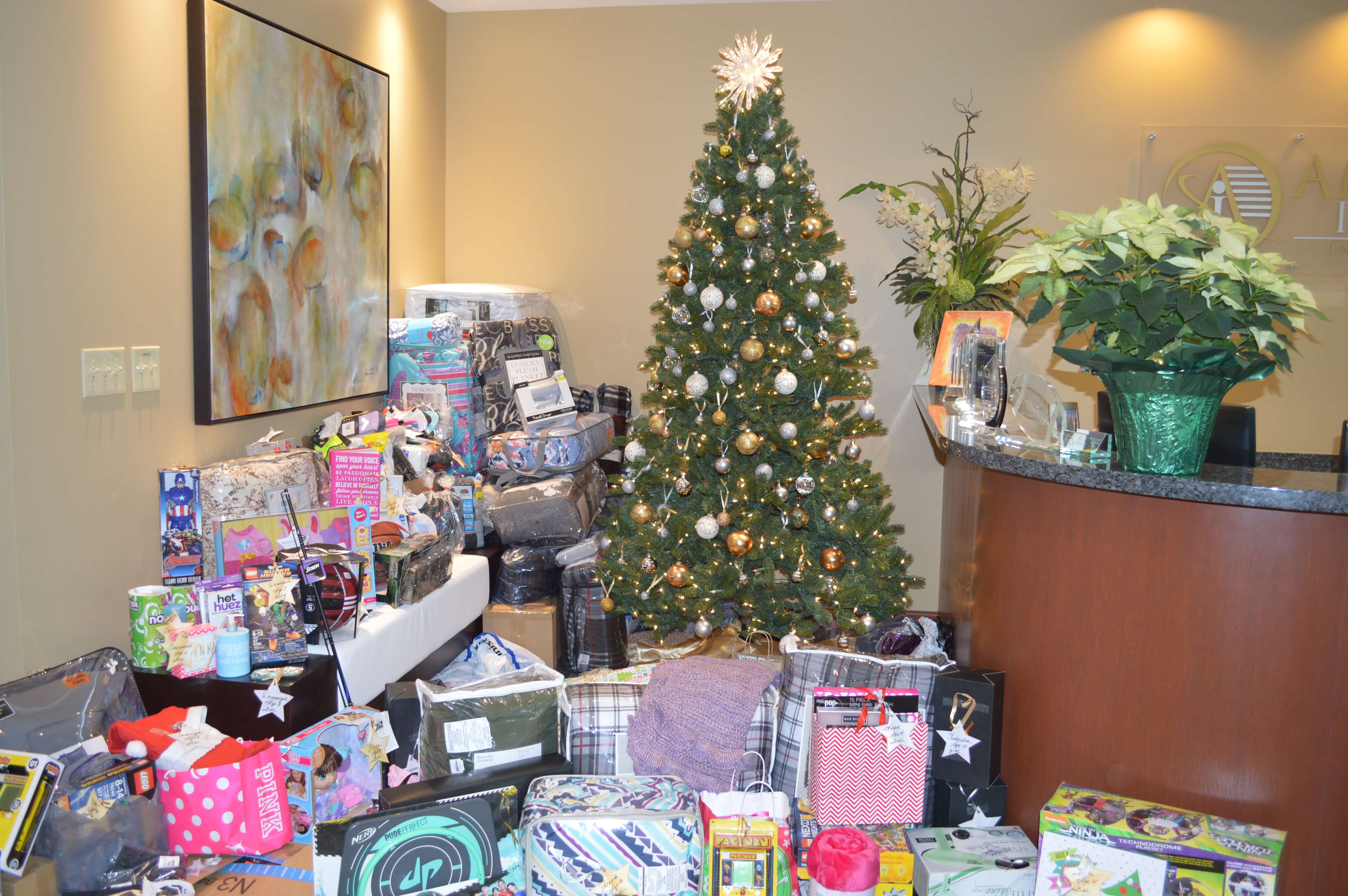 A Christmas tree in the lobby of the American Integrity office, surrounded by gifts intended for donation at the Joshua House