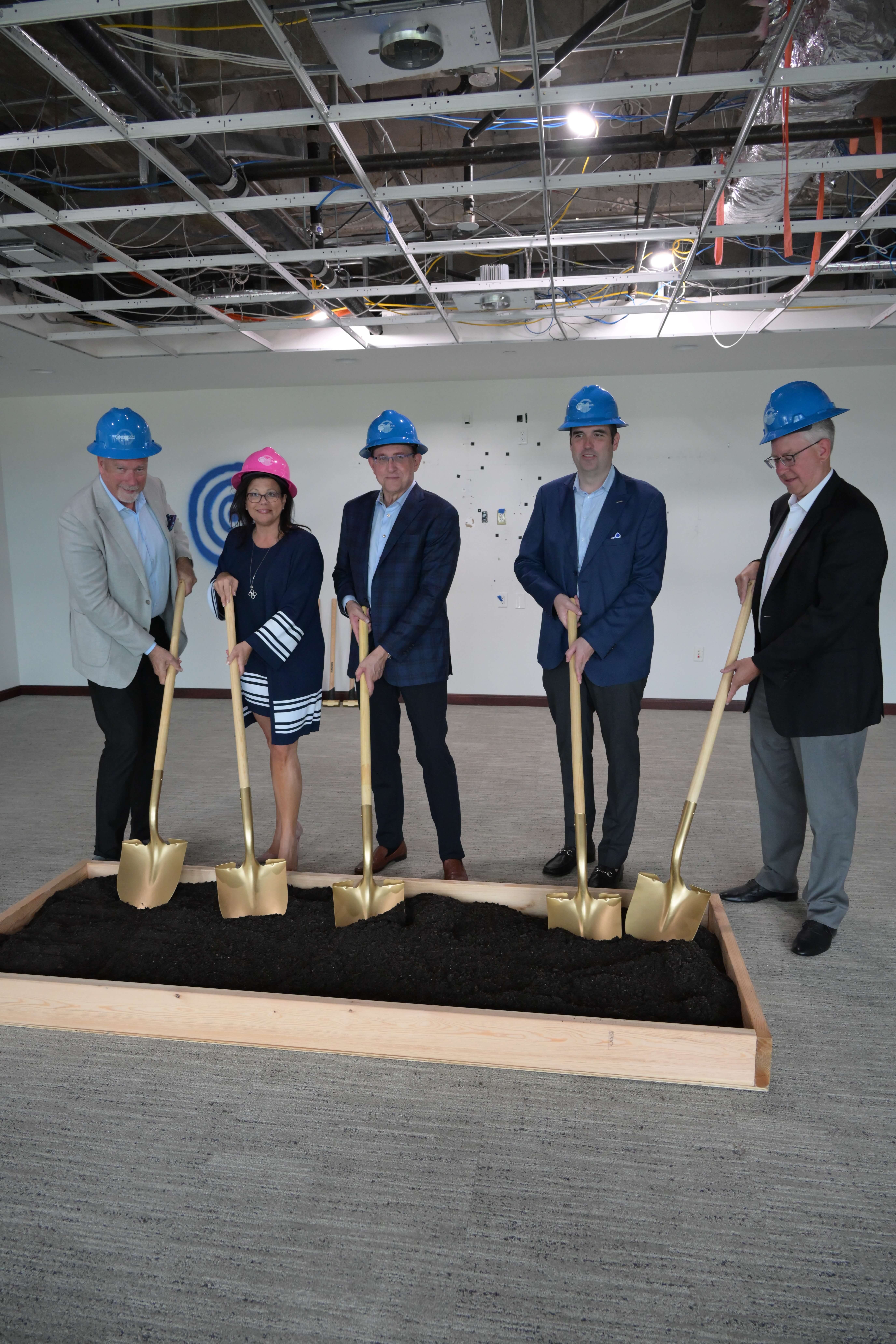 Members of the American Integrity leadership team pose in hard hats with shovels to commemorate the groundbreaking of the new headquarters